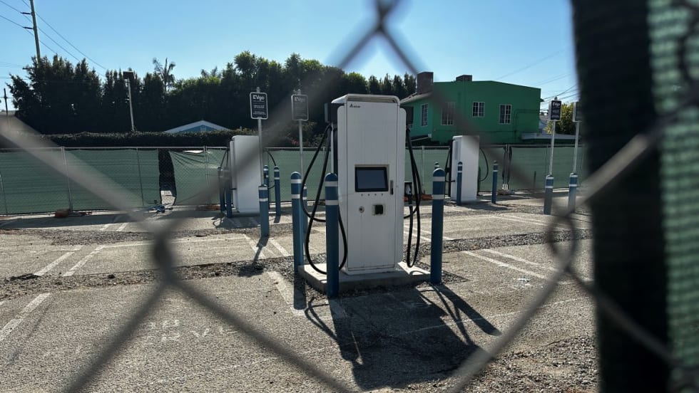Empty EV chargers behind a chain link fence. 