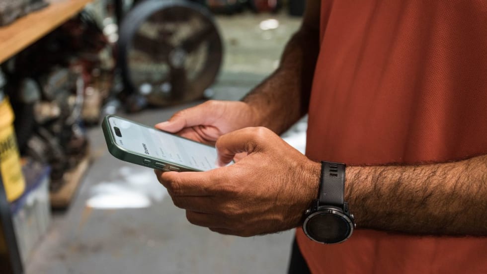 Person holds phone in both hands to read safety analytics for fleets.