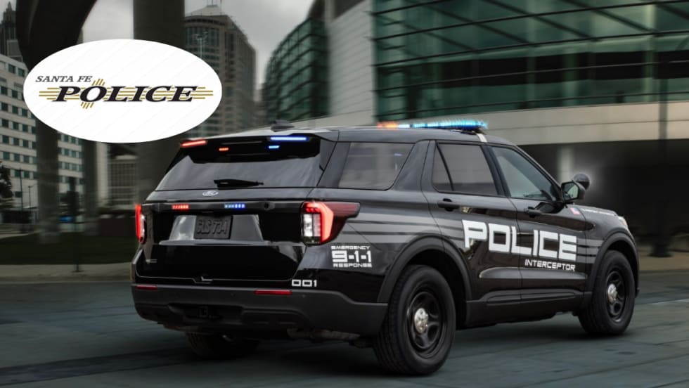 A black Ford Police Interceptor Utility is shown driving down a road.