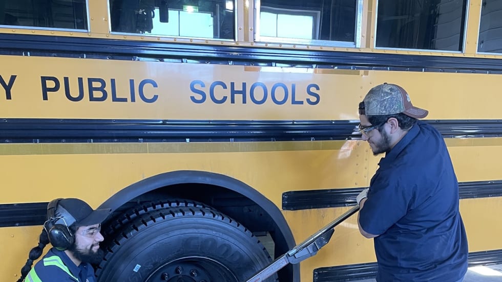 two men work on a school bus