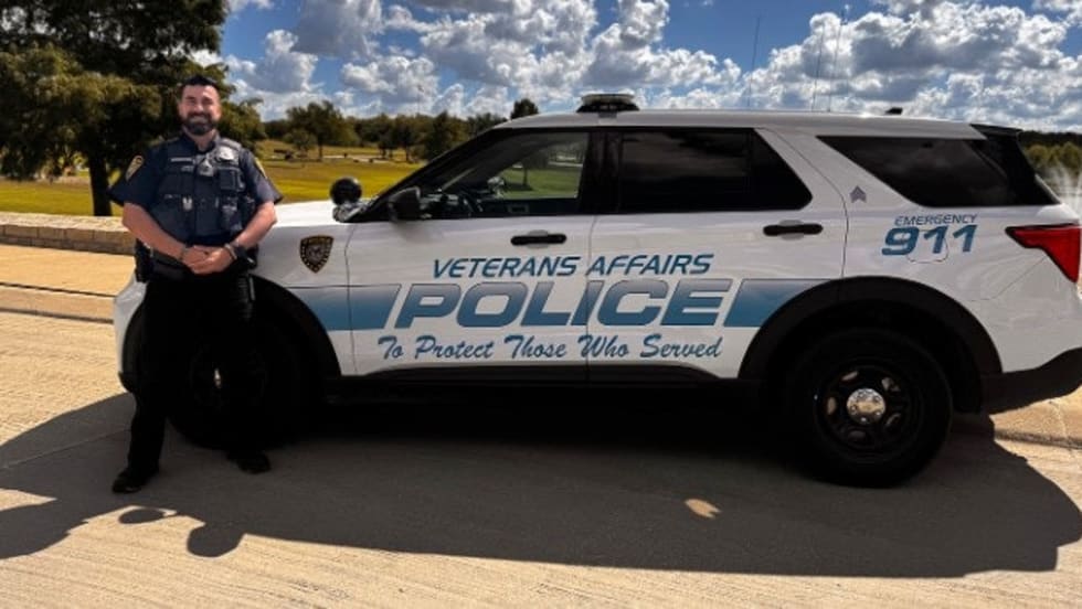 Veterans Affairs Police SUV with officer standing beside white patrol vehicle on sunny day