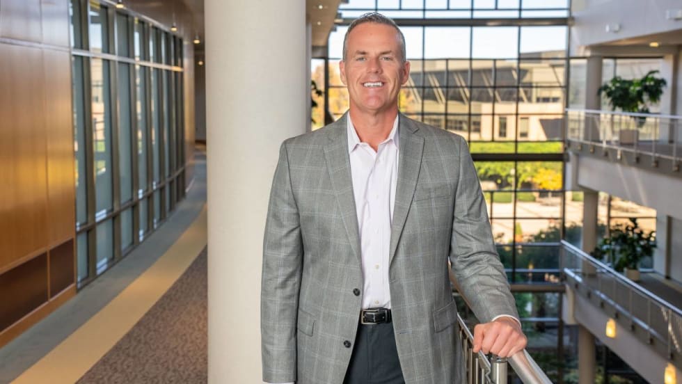 Shawn Concannon along second floor of atrium of office building with tall glass windows.