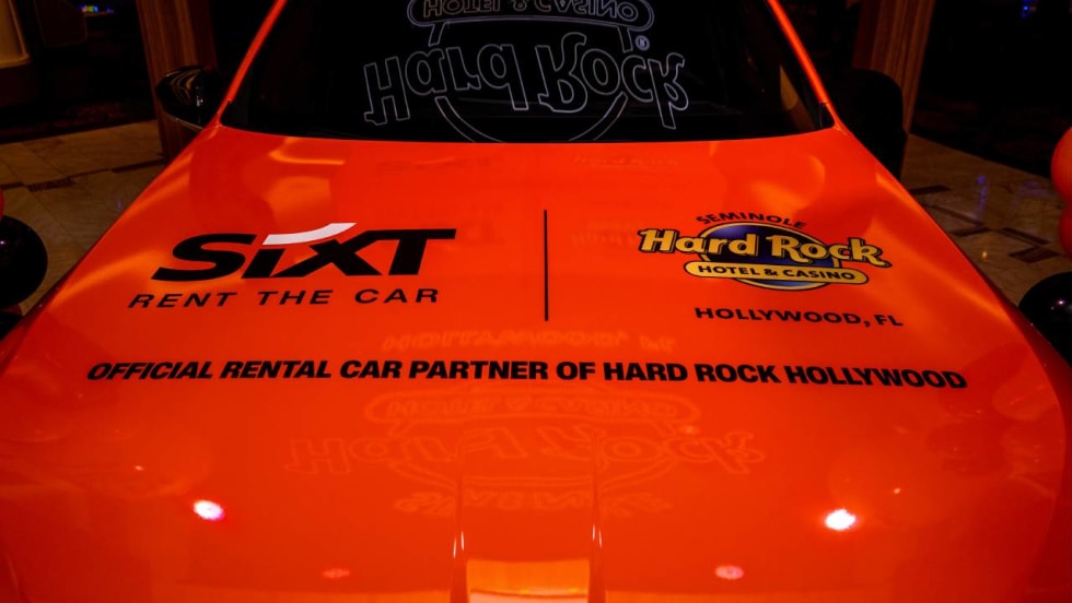 A red hood of a car with SIXT and Hard Rock logos.