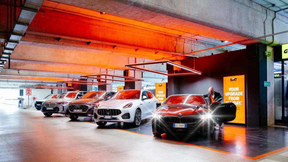 Rental car customer getting into a car parked in a line of SIXT rental cars at an airport in Milan, Italy.
