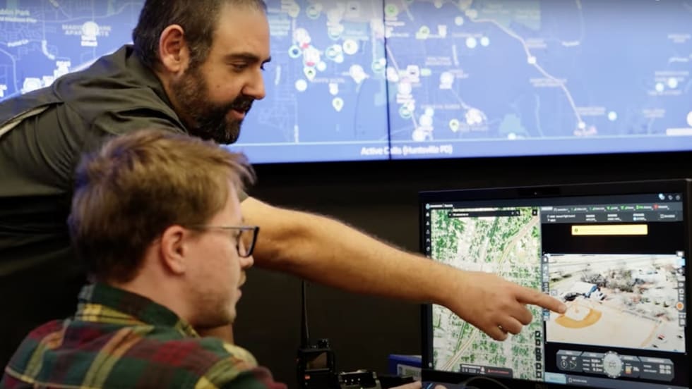 Analysts reviewing geospatial data on multiple computer screens in a monitoring center