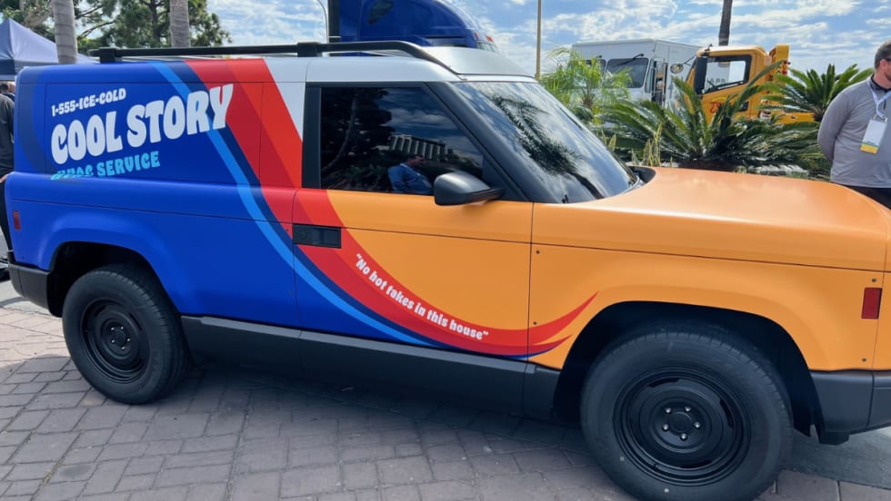 A side view of the yellow, blue, and red Slate Auto electric pick-up truck and SUV