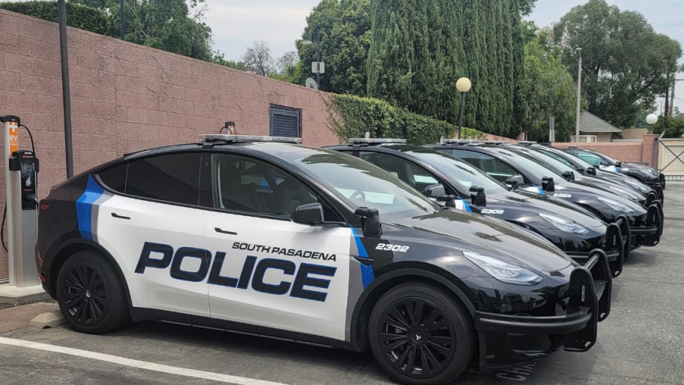 Tesla Model Ys and 3s are shown lined up in a parking lot. They are upfitted with police equipment and have South Pasadena Police decals on them.