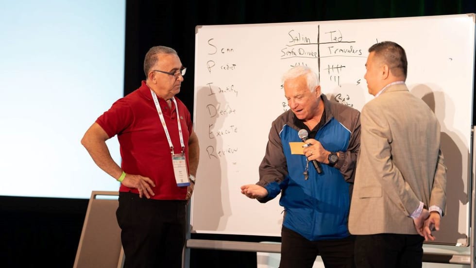 ImprovLearning instructor Steve Verret on stage with two fleet managers.