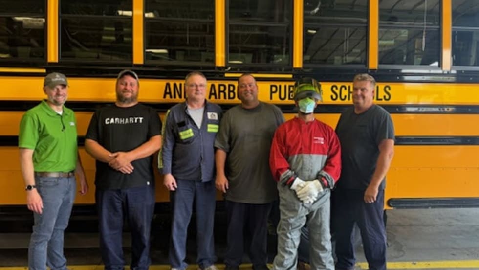 a group of people stand in front of a school bus