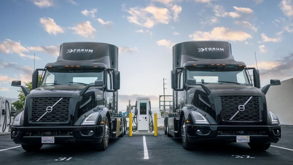 photo of two Volvo electric trucks at a Forum Mobility charging station
