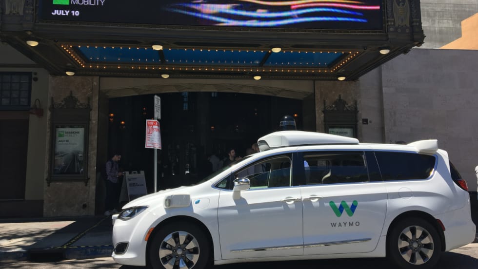 Waymo minivan in front of a theater.