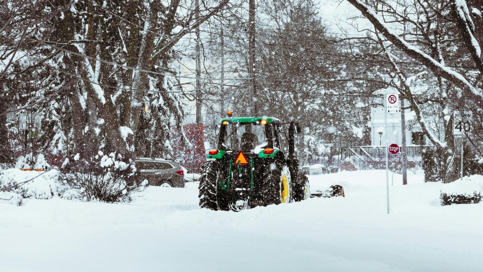 A snow plow in the winter while it snows