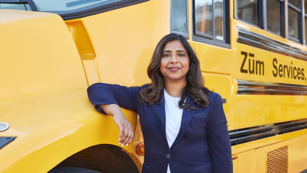A woman stands in front of a school bus