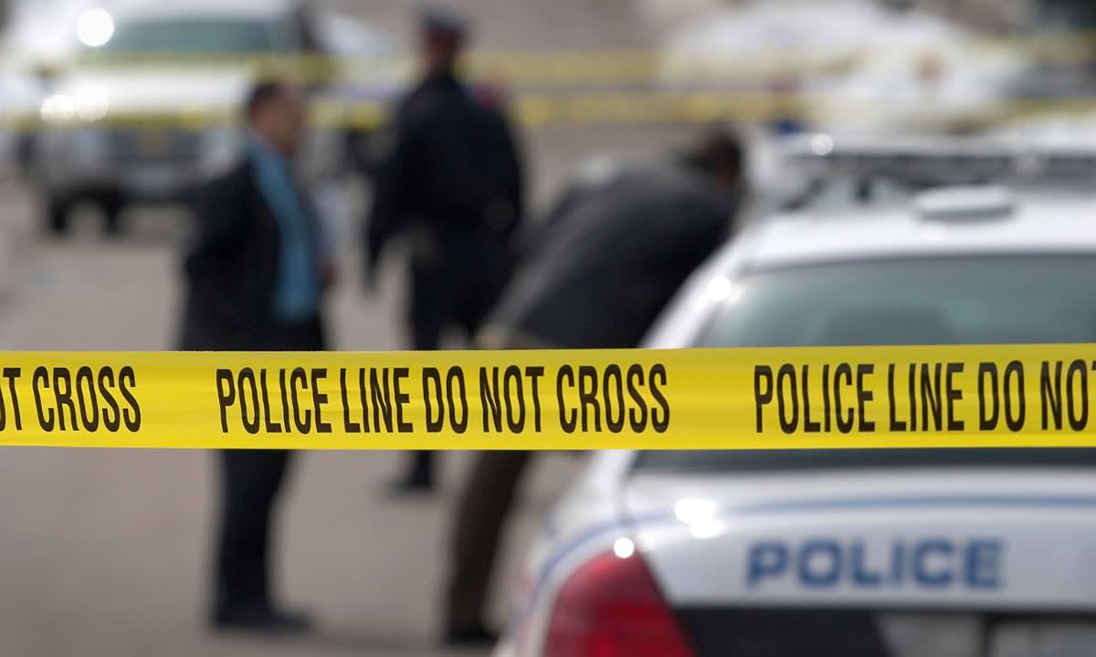 Yellow police tape cordoning off a crime scene with police vehicle
