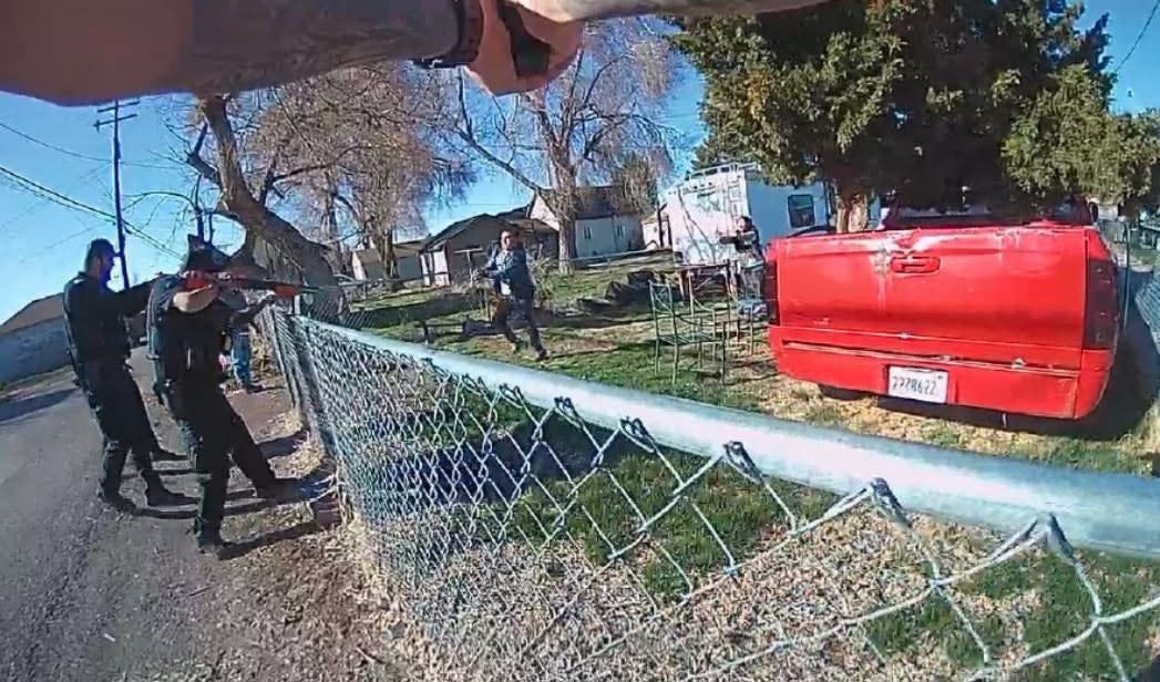 Law enforcement officers near chain-link fence with red truck in residential neighborhood