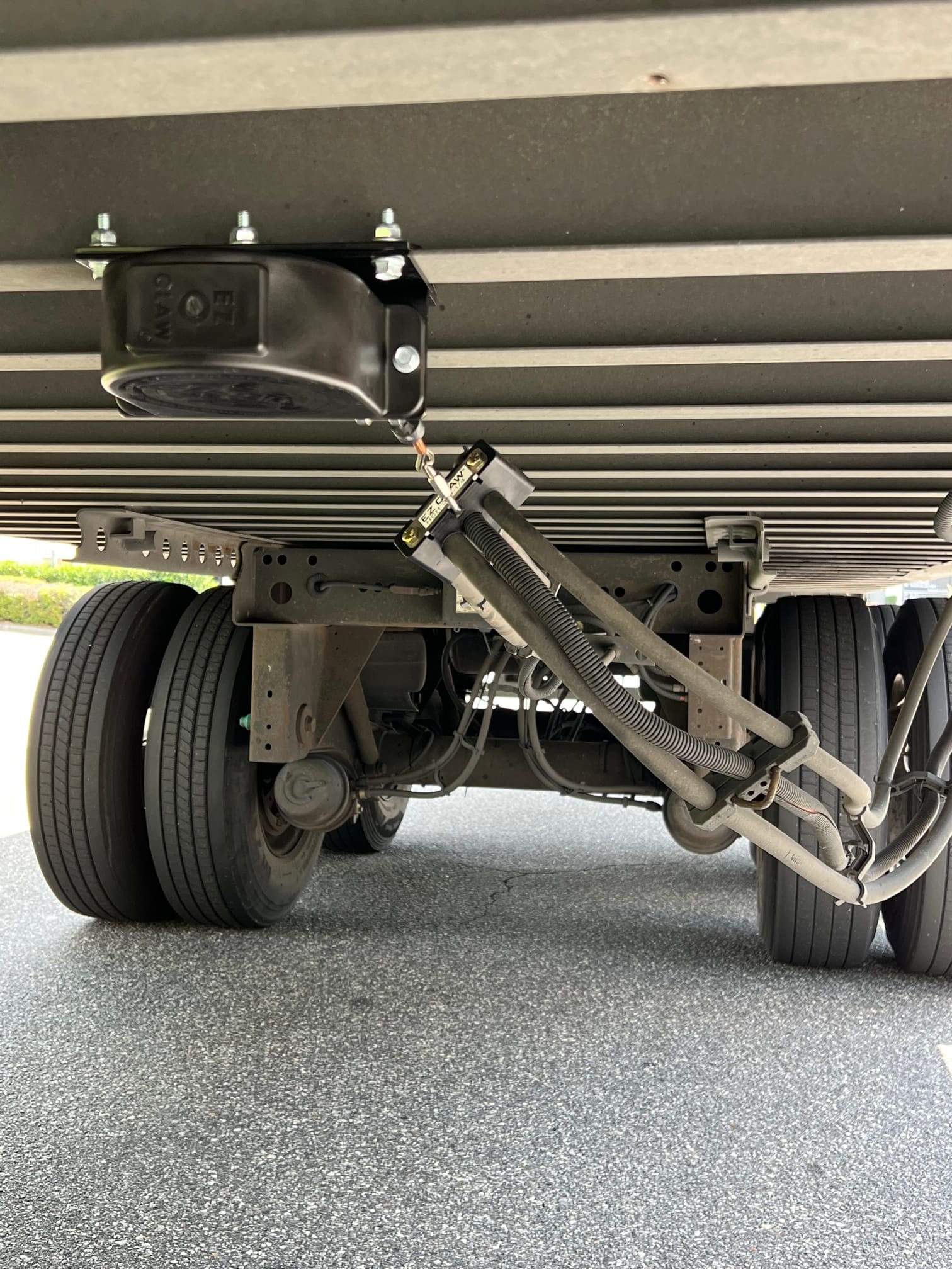 Black EZ Claw Line Saver monted to underside of a utility trailer with hoses or wiring attached