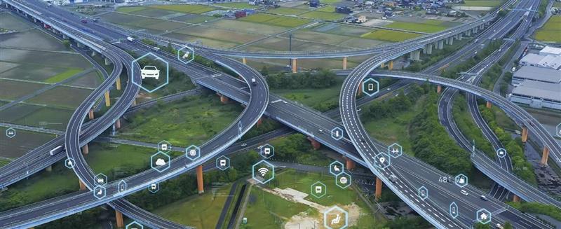 Aerial view of a large highway interchange with digital smart-mobility icons overlaid.