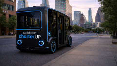 A black and blue HOLON urban autonomous vehicle on a city street.