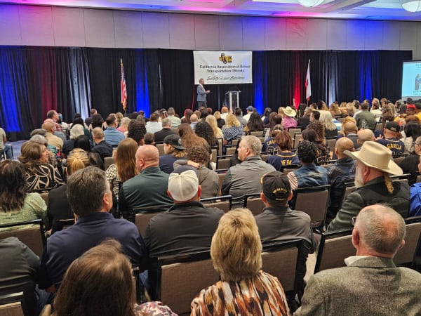 Wide view of a packed ballroom at the CASTO 2026 conference as a keynote speaker presents on stage beneath a “Safety Is Our Business” banner, with attendees seated and listening.