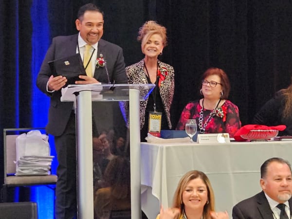 Award recipient smiles at a podium while holding a plaque during a formal recognition ceremony at the conference banquet.