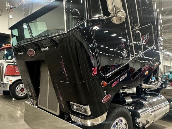 Black Peterbilt cabover with cab tilted forward to reveal engine