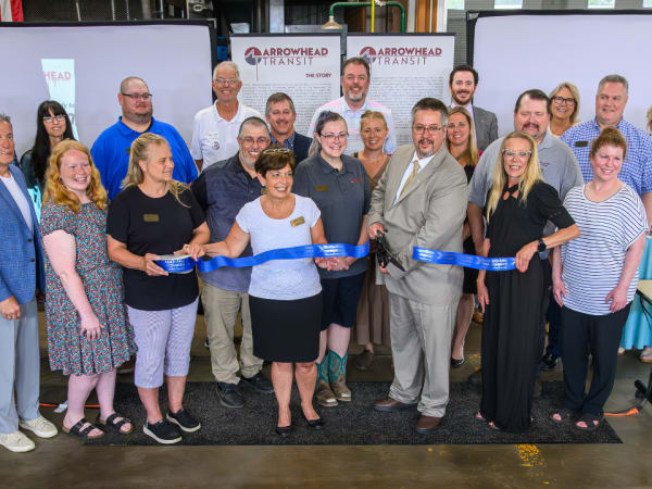 Business and community members pose during a ribbon cutting.