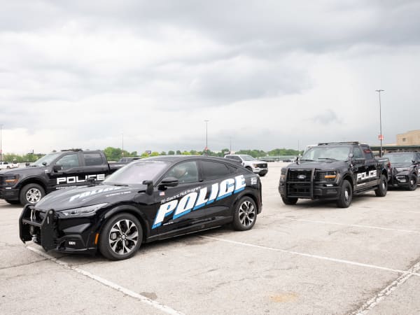 Three black upfitted Ford pursuit-rated vehicles are lined up in a parking lot.