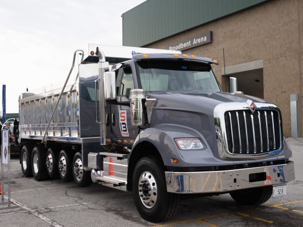 An International Truck HX620 with an S13 Integrated Powertrain, loaded with a dump body, sits in the Vehicle Showcase lot for attendees to see close up.