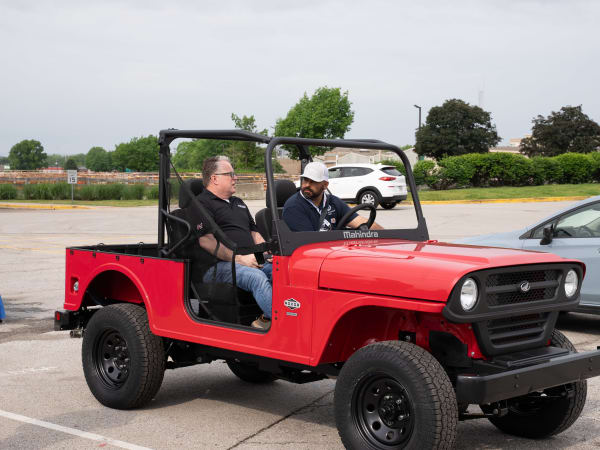 Two people sit in a red Mahindra ROXOR, ready to test drive it.