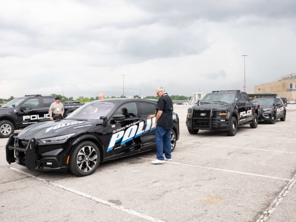 A lineup of police vehicles waiting to be test-driven is shown. They include a Ford Mustang Mach-E, a Ford F-150 Police Responder, and a Ford Police Interceptor Utility.