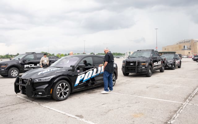 A lineup of police vehicles waiting to be test-driven is shown. They include a Ford Mustang Mach-E, a Ford F-150 Police Responder, and a Ford Police Interceptor Utility.
