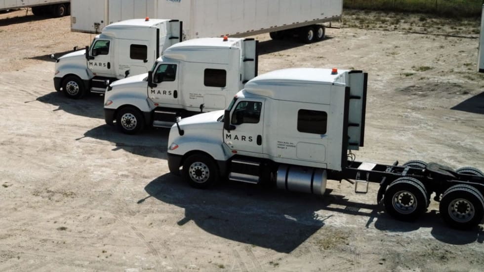 Three white trucks parked in a row