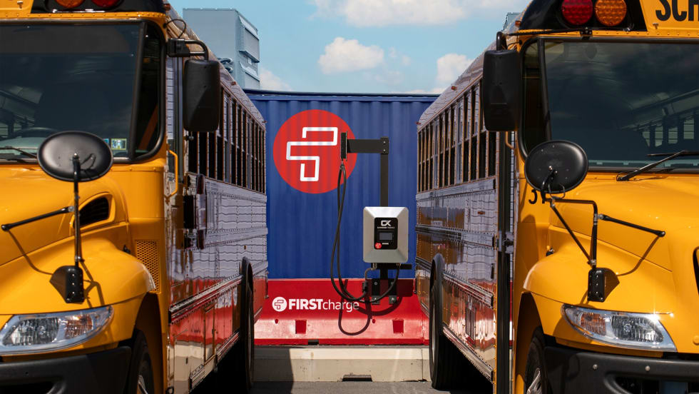 two school buses plugged into a charging station