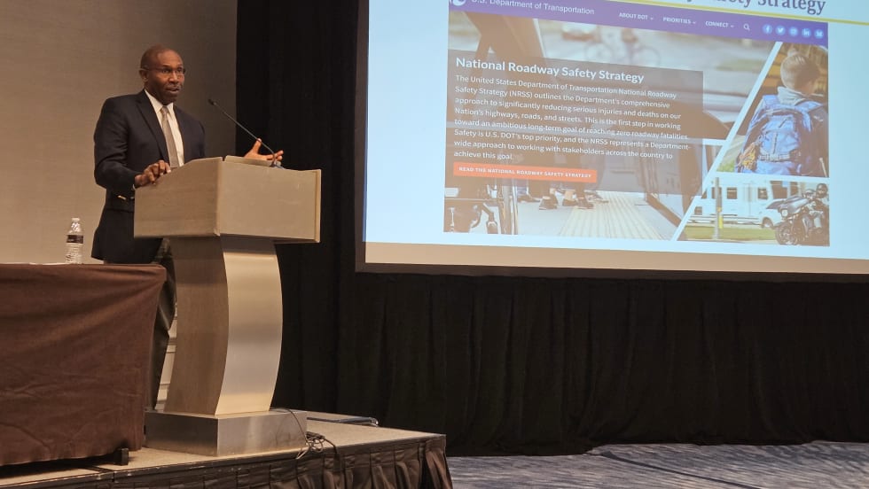 A man stands at a podium and presents to a crowd