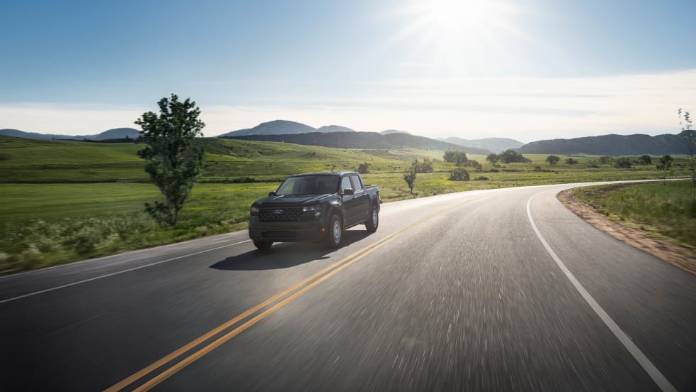 A black Ford Maverick XL is shown driving down a rural road.
