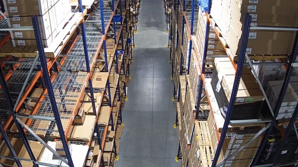 Warehouse aisle with pallet racking filled with boxed inventory at a distribution center.