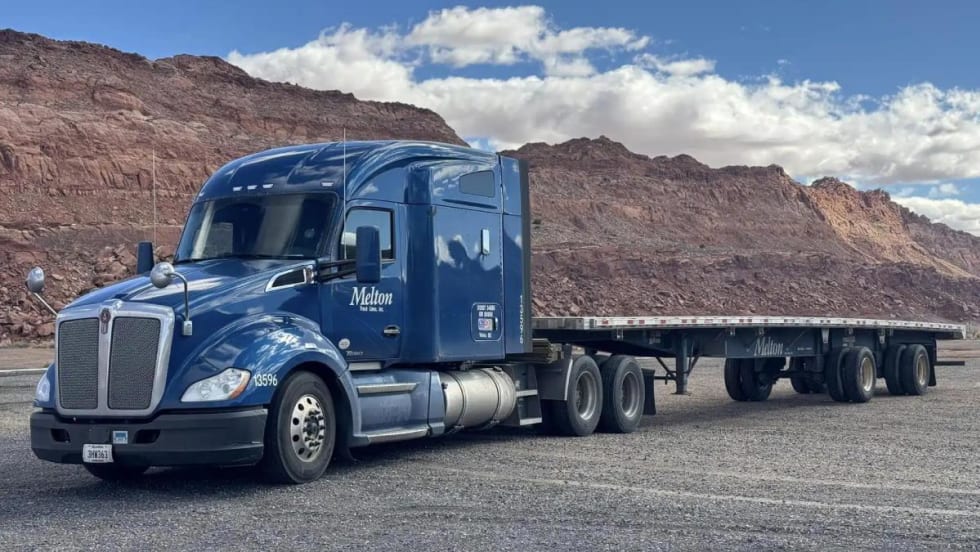 Blue heavy-duty tractor pulling a flatbed trailer