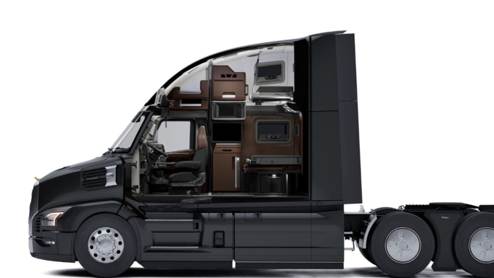 Side cutaway view of a Mack Pioneer truck cab showing the driver’s seat and sleeper area with storage cabinets, microwave, bunk beds, and workspace inside the cab interior.