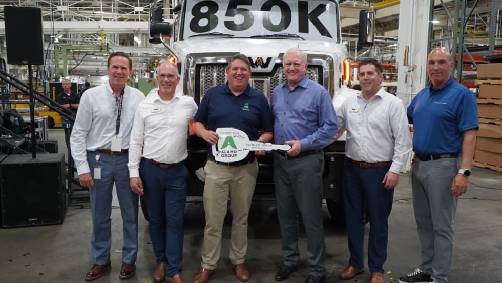 Six men stand in front of a Western Star truck marked “850K” at DTNA’s Cleveland plant, holding a ceremonial key for the 850,000th truck delivered to Alamo Group for snow and ice operations.