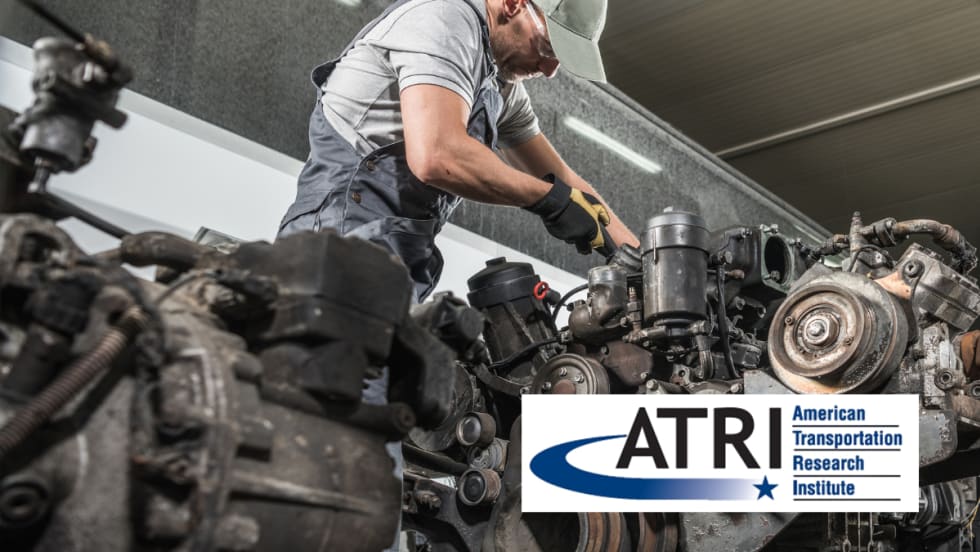 A diesel technician works on a large engine in a repair shop, wearing gloves, safety glasses, and a cap, with the ATRI (American Transportation Research Institute) logo overlayed in the foreground.