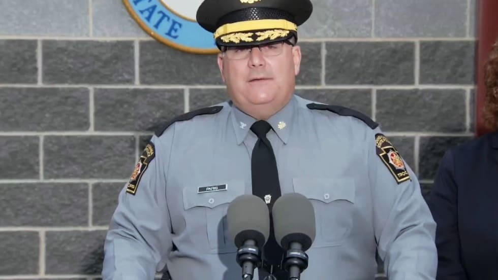 Pennsylvania State Police officer speaking at podium with official seal behind