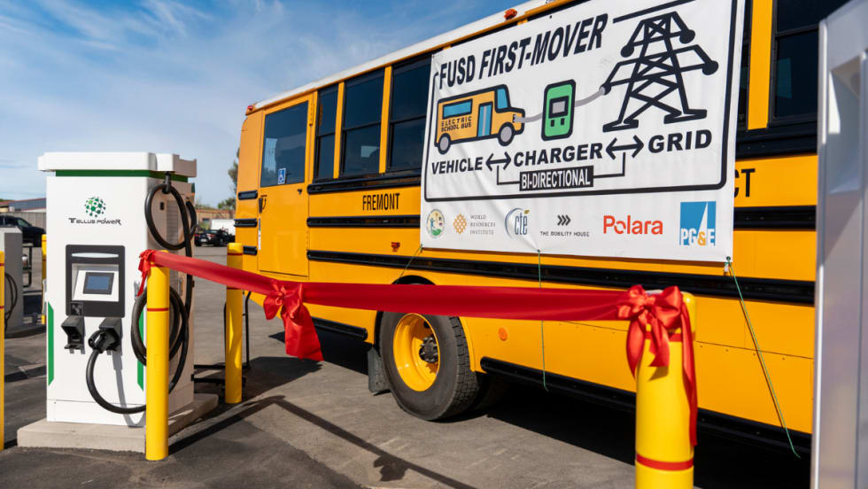 Fremont USD electric school bus next to a Tellus Power bidirectional charger with ribbon, marking launch of V2G system to support grid resilience and clean energy initiatives.