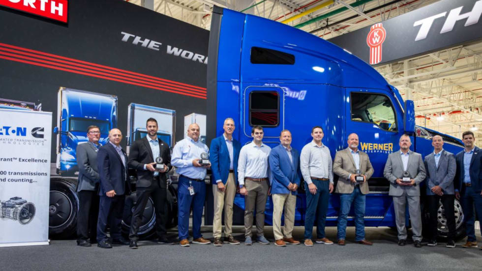Group of Eaton Cummins and Werner Enterprises representatives standing in front of a blue Kenworth T680, commemorating the 500,000th Endurant transmission milestone.