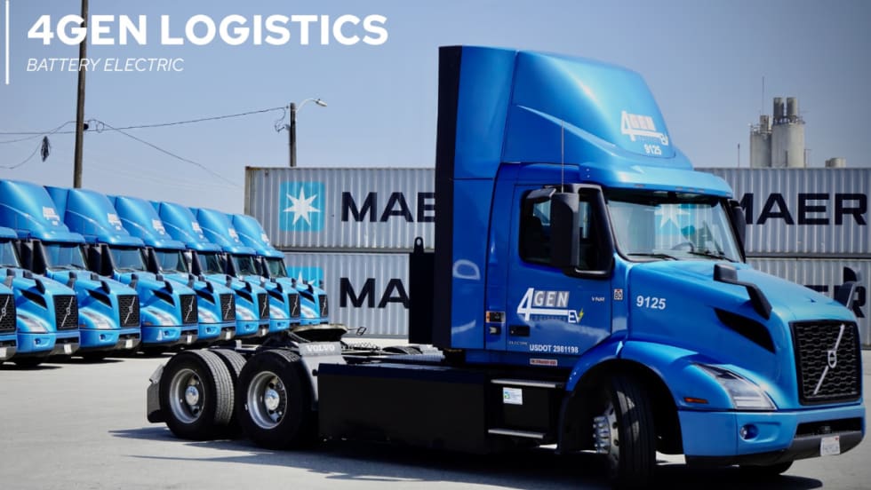 A row of blue Volvo VNR battery-electric trucks operated by 4GEN Logistics parked in front of Maersk shipping containers at a logistics yard.