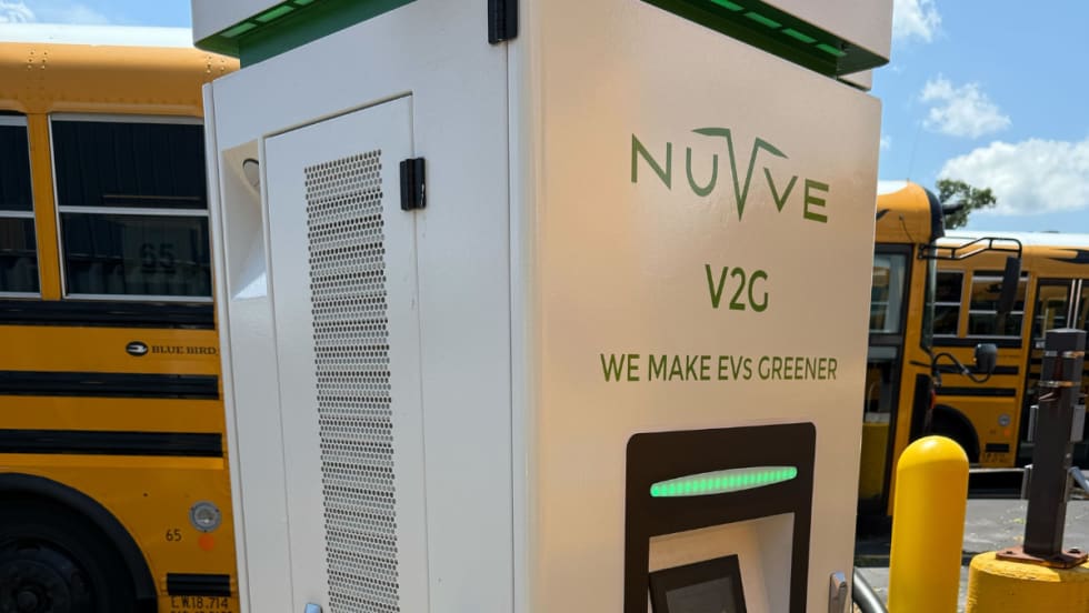 photo of a school bus charging at a Nuvve-branded EV station