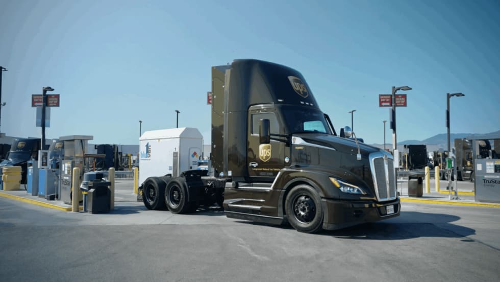 A UPS compressed natural gas (CNG) tractor is parked at a fueling station under clear skies, showcasing the company’s use of alternative fuel vehicles in its delivery fleet.