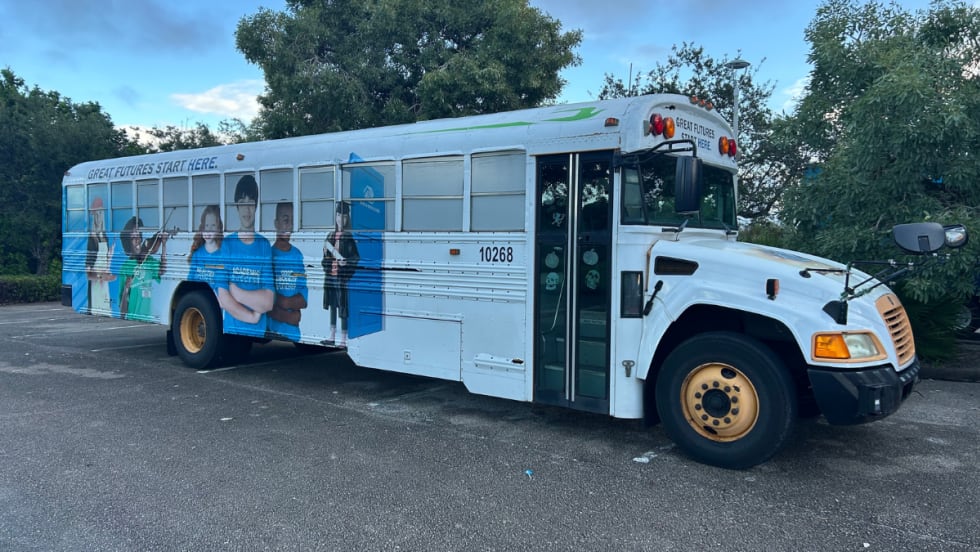 A Blue Bird Vision propane school bus operated by the Boys and Girls Club of Martin County, featuring exterior graphics of students and the slogan “Great Futures Start Here,” parked in a Florida lot.