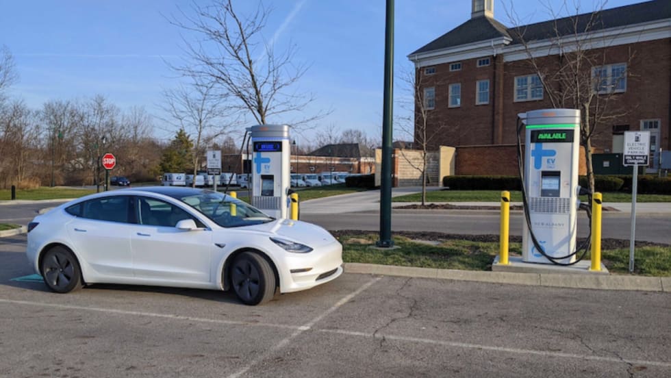 An electric vehicle charges at a public EV charging station outside a municipal building.