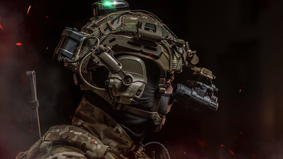 side view of a ballistic helmet in studio setting, black background, with sparks and smoke
