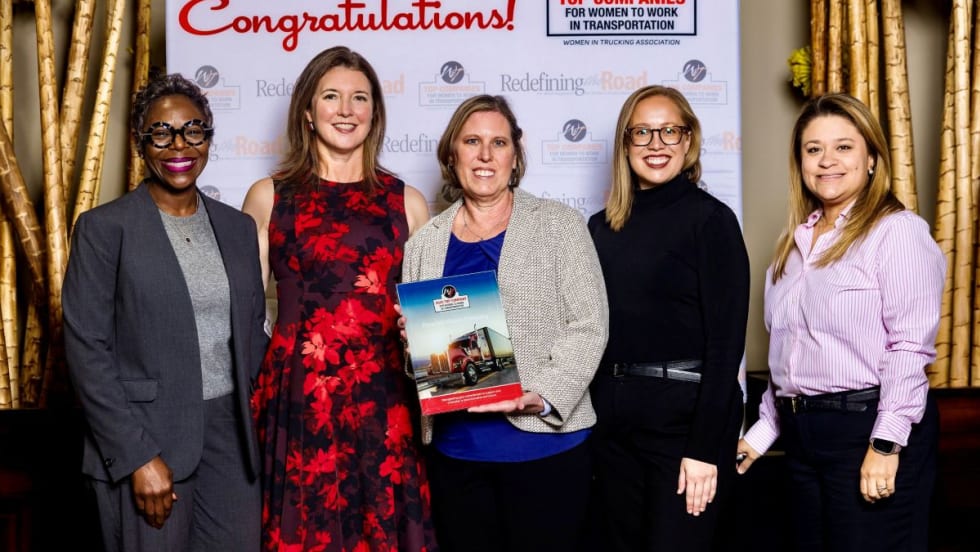 Five Peterbilt representatives pose with an award plaque after the company was named a 2025 Top Company for Women to Work in Transportation by the Women In Trucking Association.